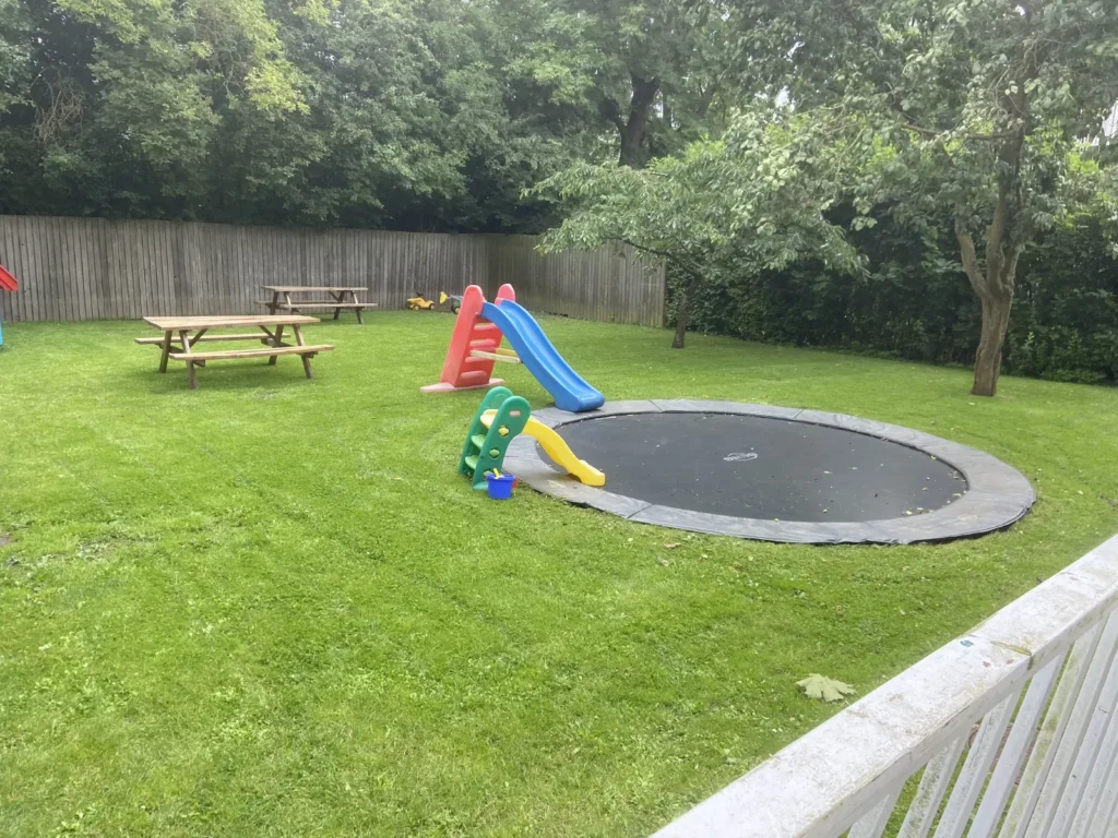 Nyslået græs på fællesareal med legeplads og trampolin